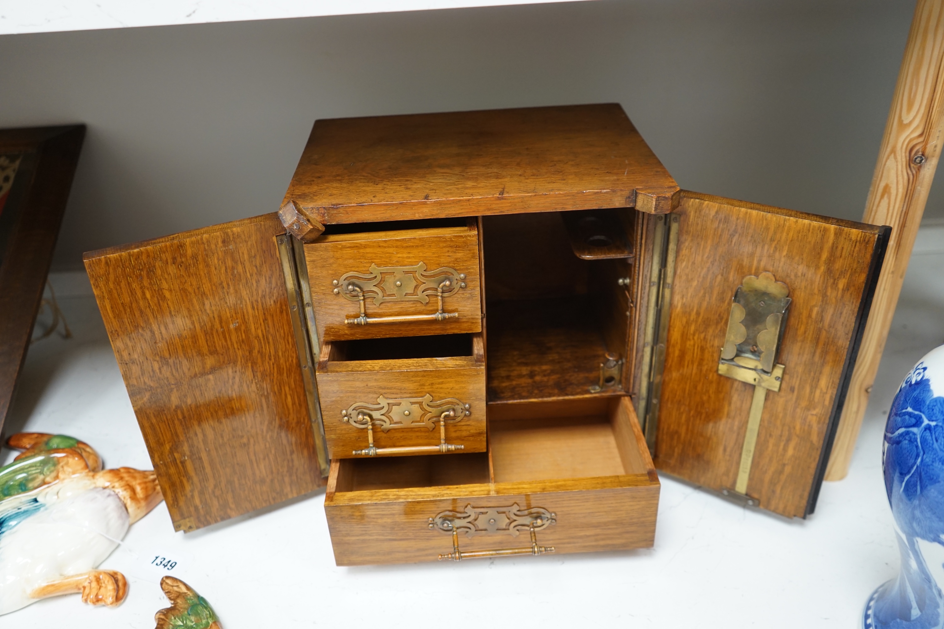 A Victorian oak cigar cabinet modelled as a safe, with brass coat of arms mounts, 30cm wide, 31cm high. Condition - fair